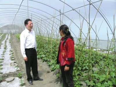 毕世祥(左)在九龙县与蔬菜种植户交谈。(资料图)